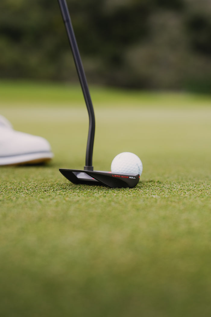 A golf ball rolling forward across a green