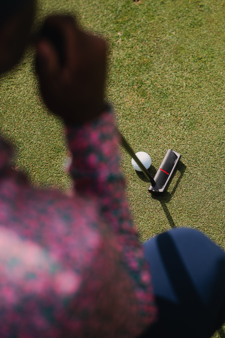 A golfer over a putt on the practice green